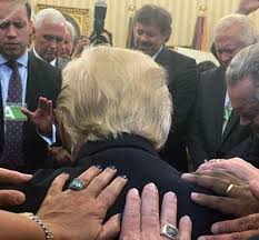A photo of president Trump recieving prayer from other ministers