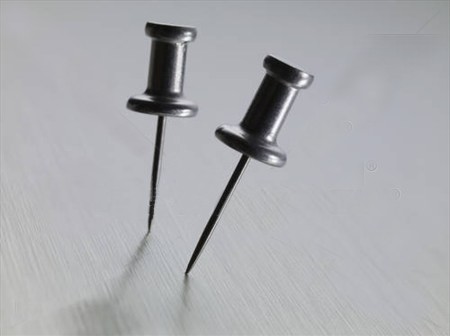 Two push pins on a smooth surface